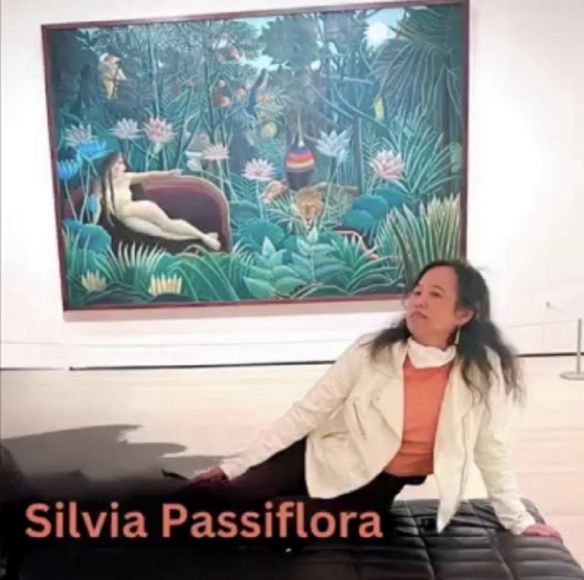 Silvia Passiflora, Southern Gothic Folk poet-songwriter, sits on at MOMA bench in front of Henri Rousseau’s painting The Dream (1910). The painting shows a lush green jungle with animals and a reclining figure on a red sofa. The photo feels quiet and reflective.