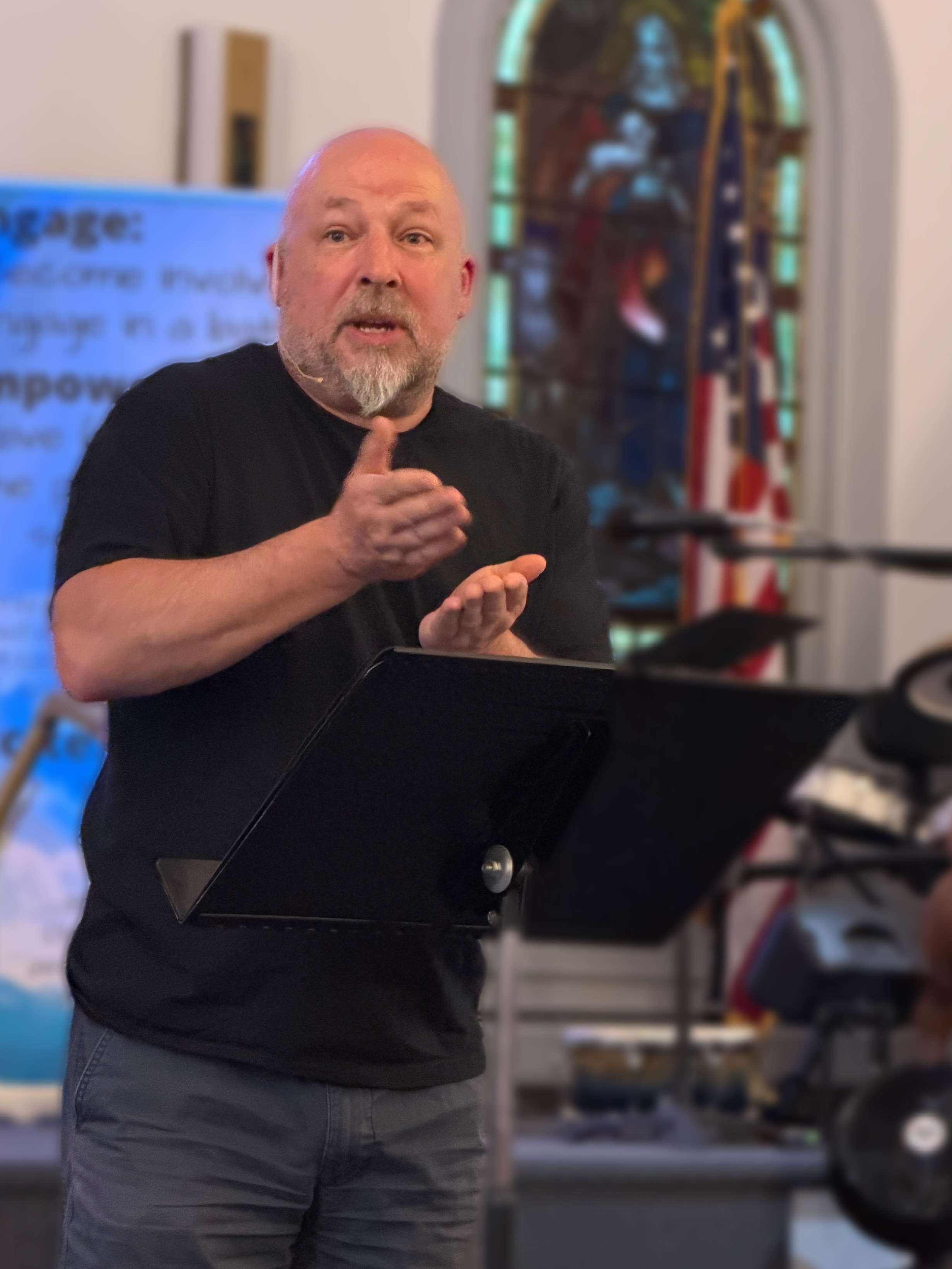 Michael standing behind a black music stand, making hand gestures while teaching