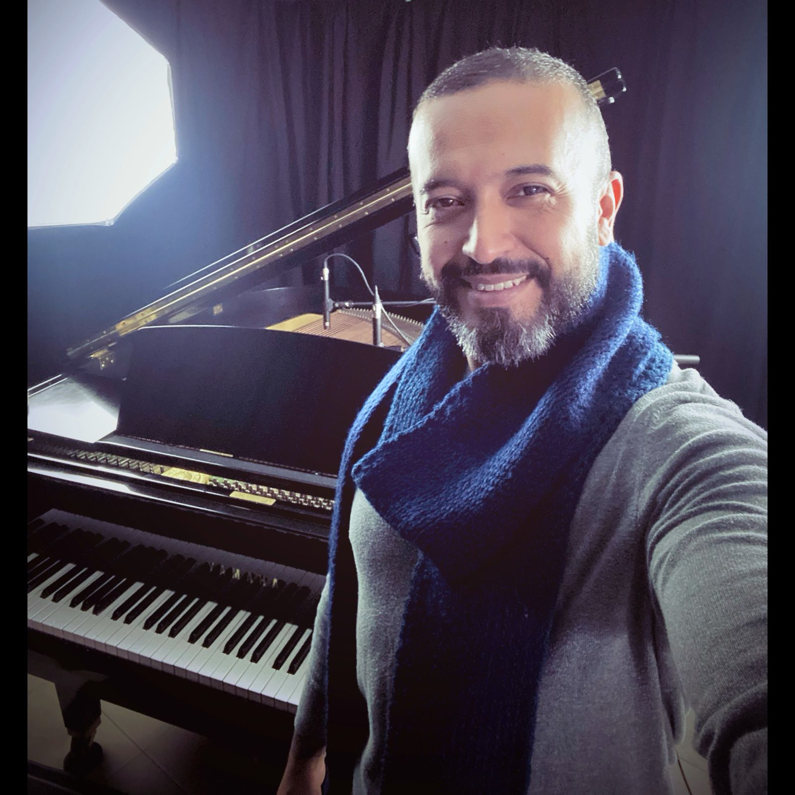 Carlos Maya beside the piano in his recording space
