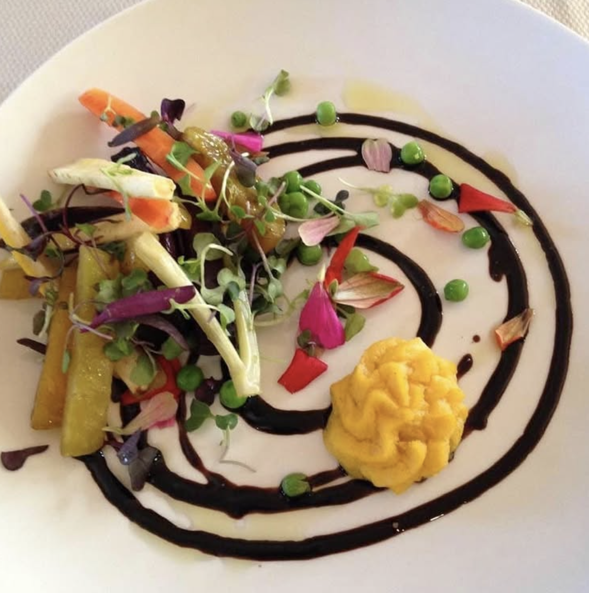 Scriptaluna — a composed fine dining vegetable plate by Word of Mouth Cooking Club, featuring heirloom carrots, fennel, fresh peas, edible flowers, microgreens, and a saffron aioli quenelle with a balsamic reduction spiral.