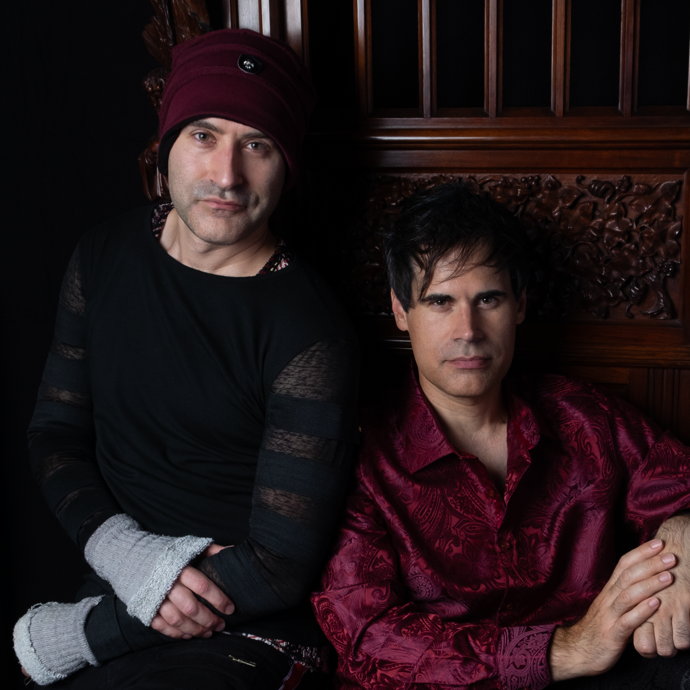 Image of Alex and Christian Sitting side by side on a gothic brown chair.