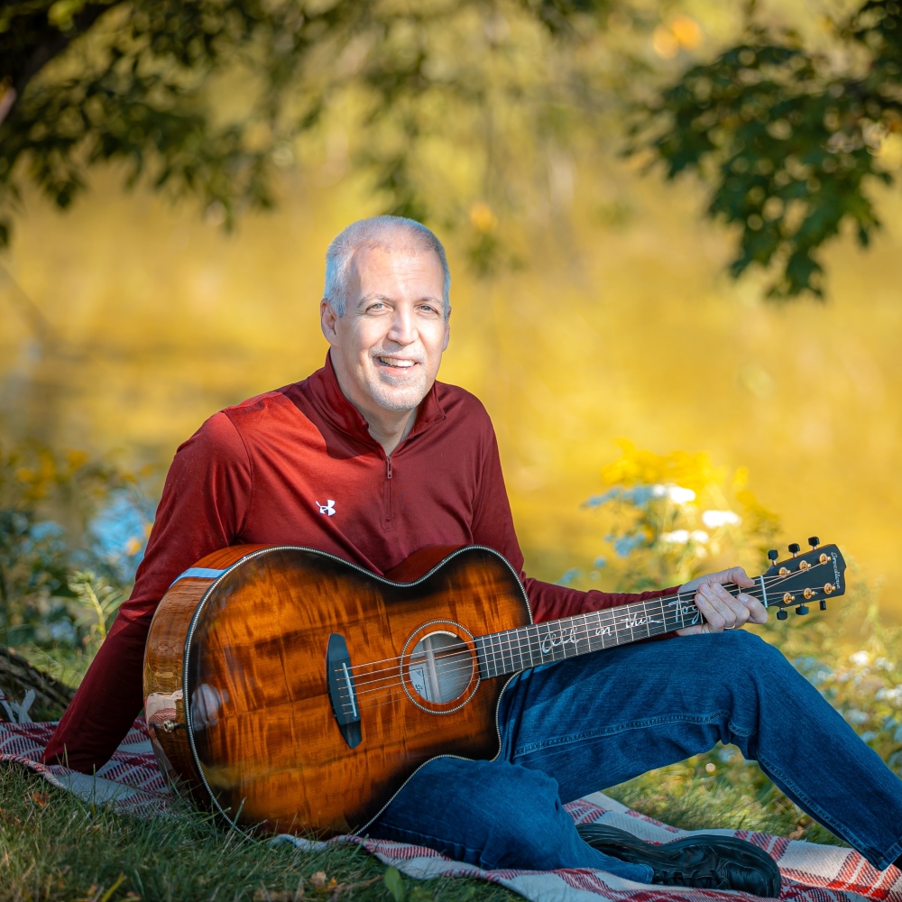 Mike Lucey Sitting on a blanket Near a Tree with a Breedlove Acoustic