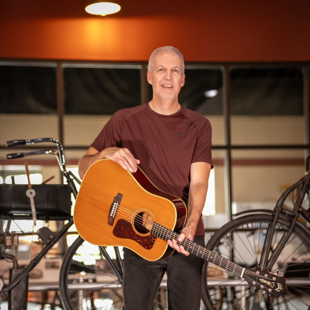 Mike Lucey at a Museum with a Guitar.