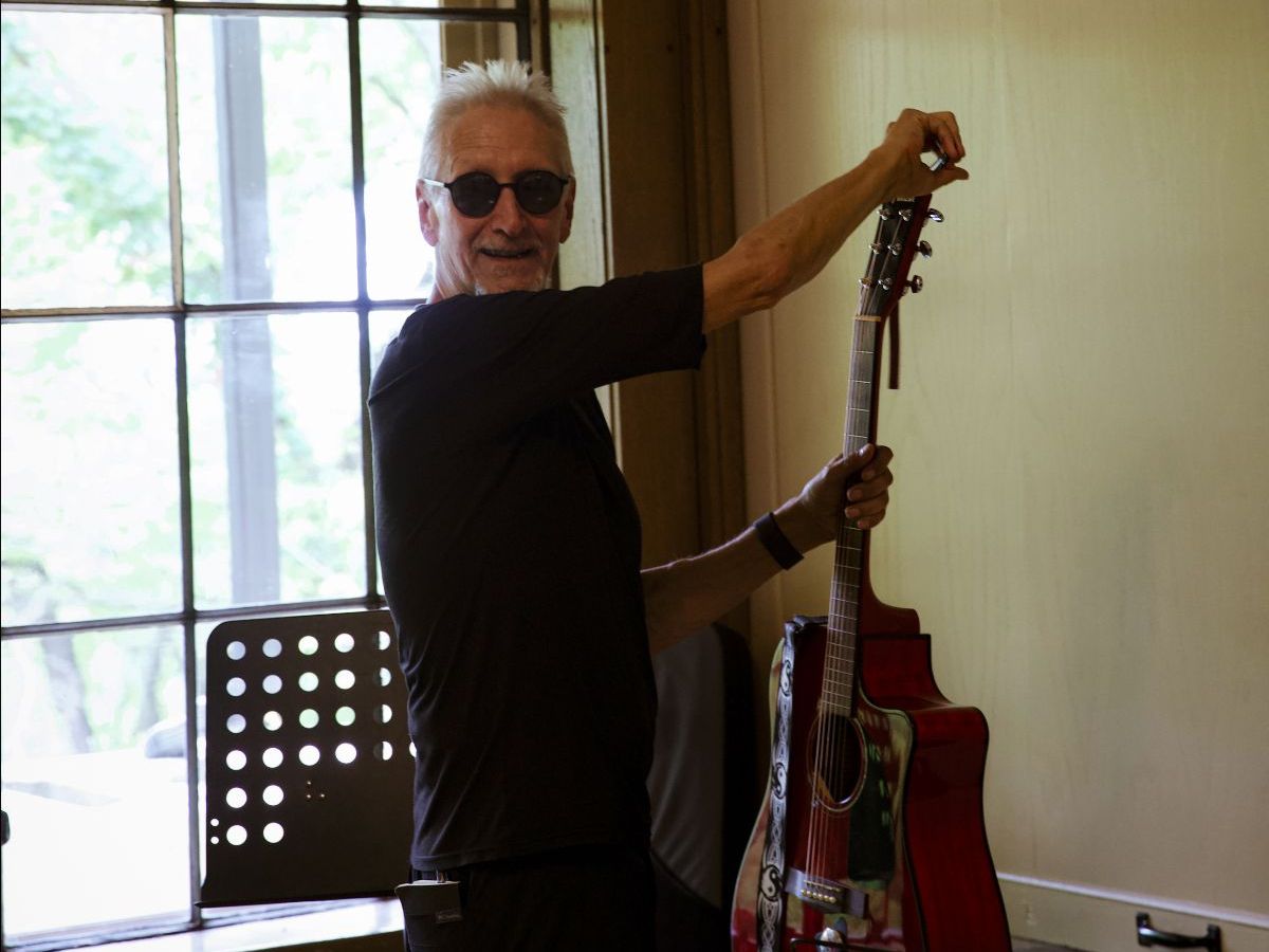 SAMI Member Joe Peters tuning a red guitar during the Keep Looking Up Songwriters Retreat in September 2025