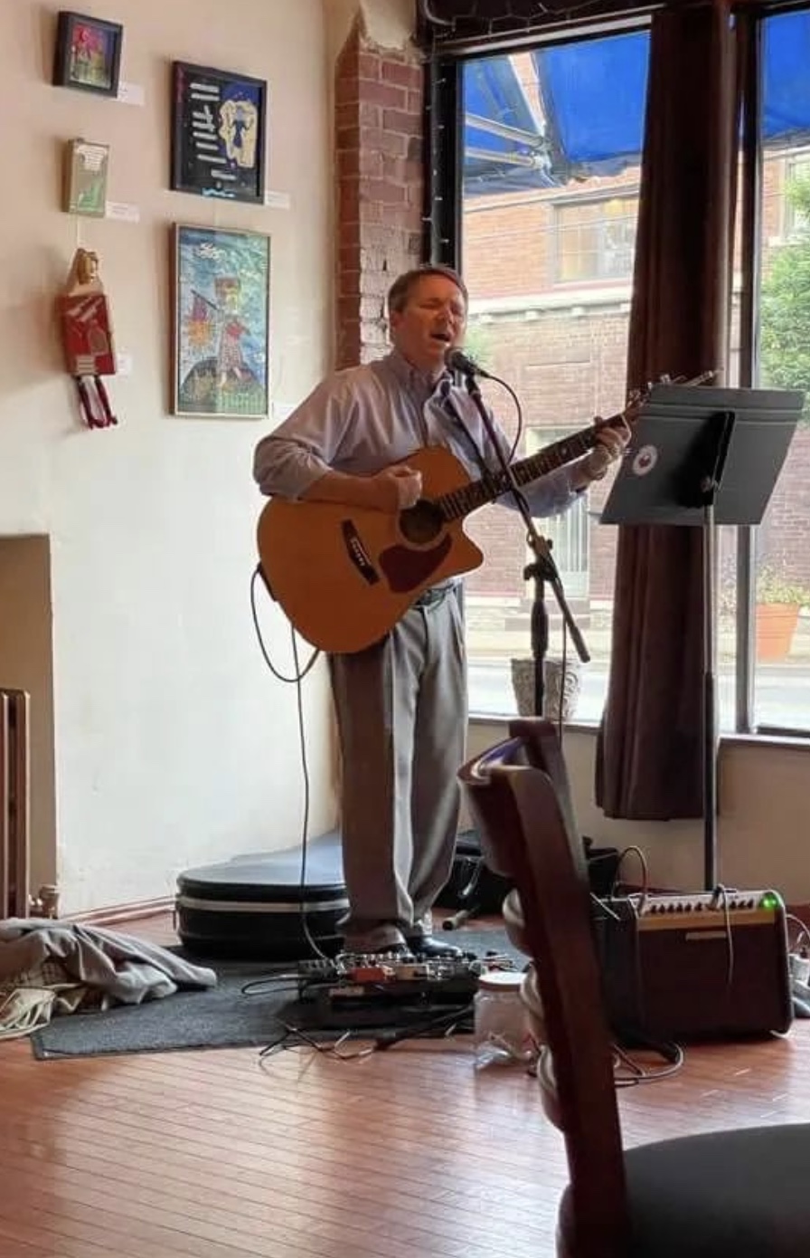 A photo of Jack Jose playing guitar and singing at Muse Café in Cincinnati