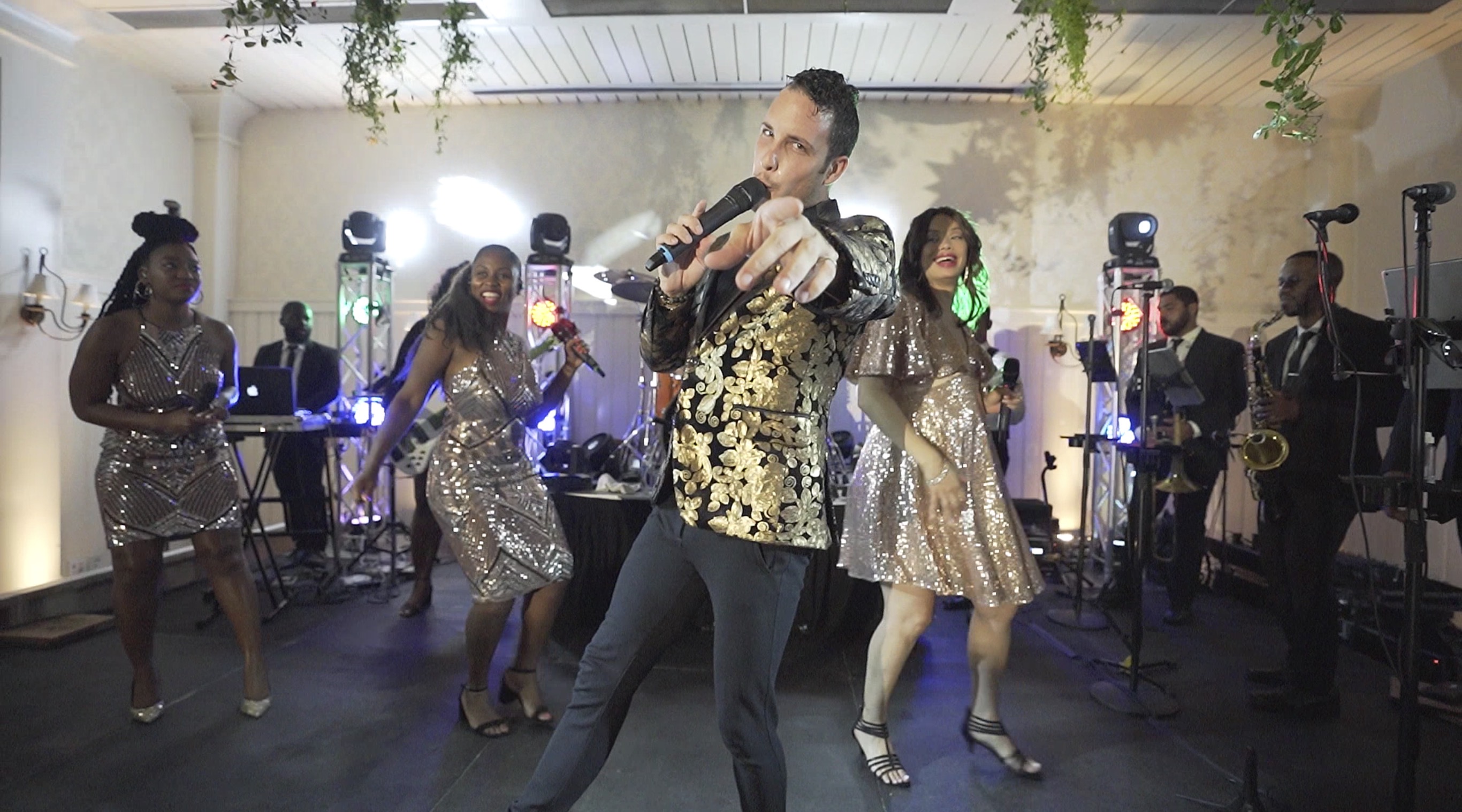 11-piece live show band with lead vocalists and brass section performing synchronized choreography on stage at an Atlanta wedding reception.