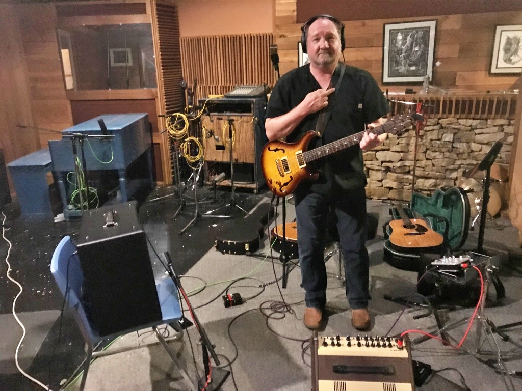 Bill in a recording studio with guitar and headphones