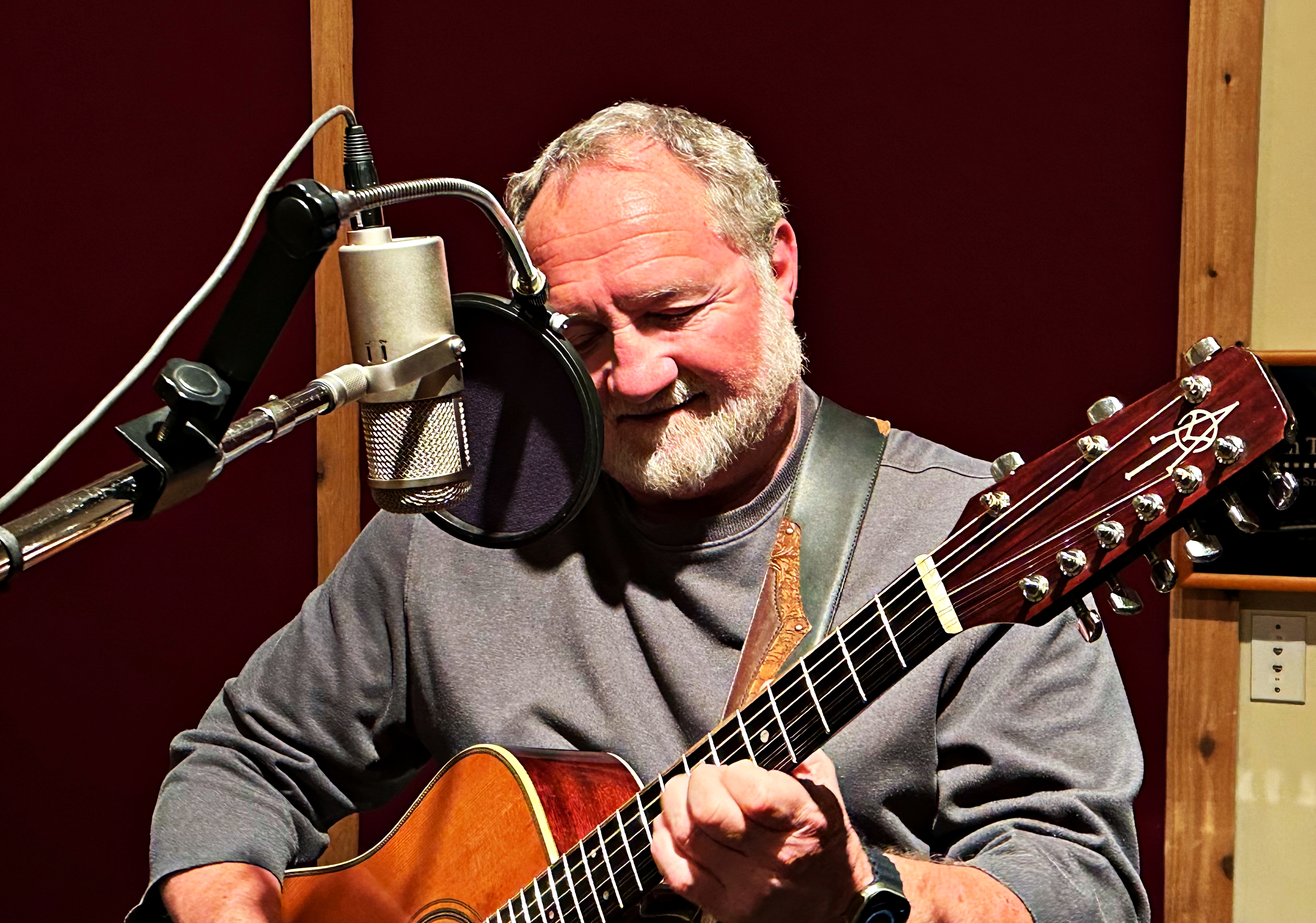Bill playing guitar at the microphone while recording MORE