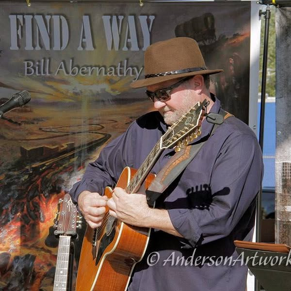 Bill performing in front of the Find a Way backdrop