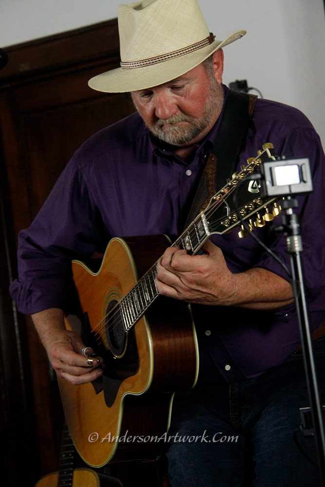 Bill playing acoustic guitar in a live performance