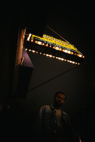Jor looking at camera. Standing under pawn shop sign