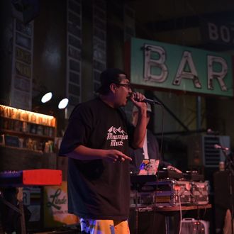 Photo of C. Boy rapping on the mic during a show.