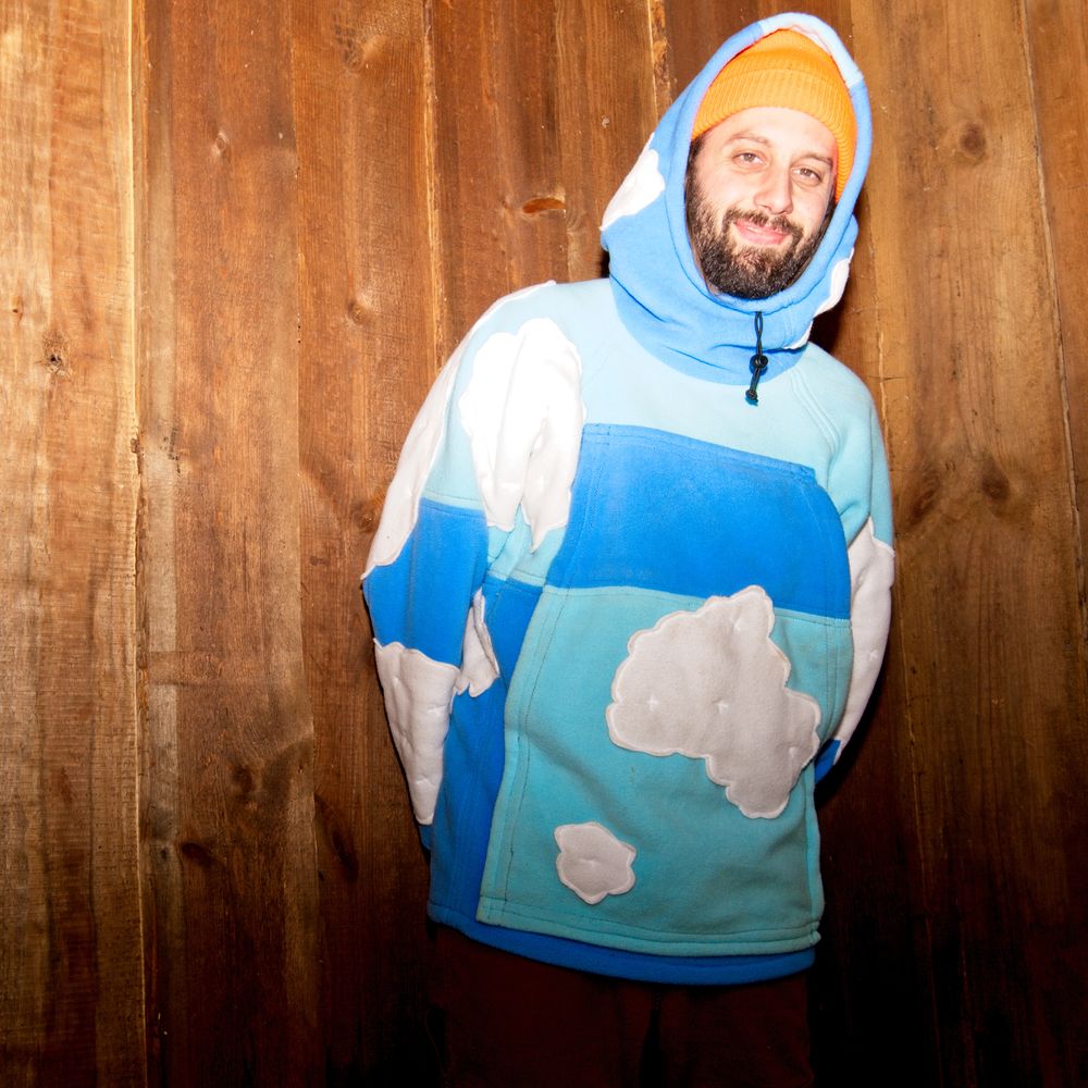 Twelve Clouds wearing a custom two-tone blue hoodie with 12 clouds on it and an orange beanie.
