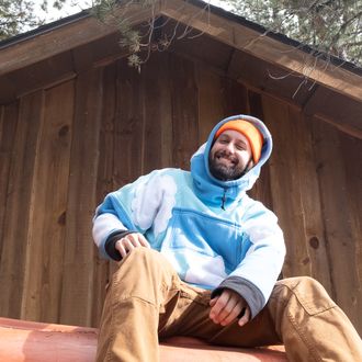 A photo of Twelve Clouds wearing a custom blue hoodie with clouds on it and an orange beanie.