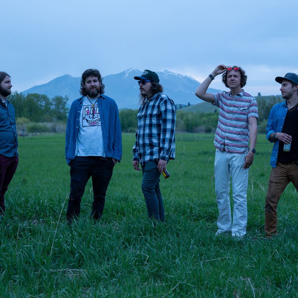 STiLGONE band members Cal, Chris, Symon, Carl, and Ezra in a field all facing different directions.