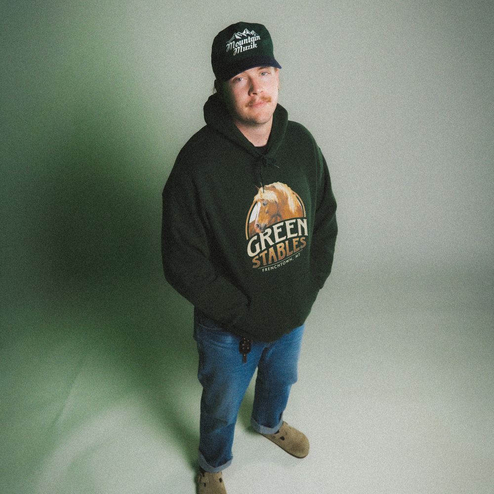 Portrait photo of Drem, wearing a brown jacket over a grey hoodie and a black beanie.