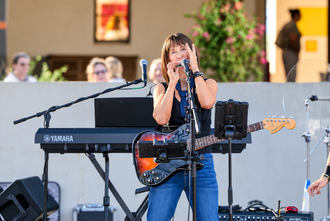 PretendAZ singer playing guitar and harmonica during a live performance