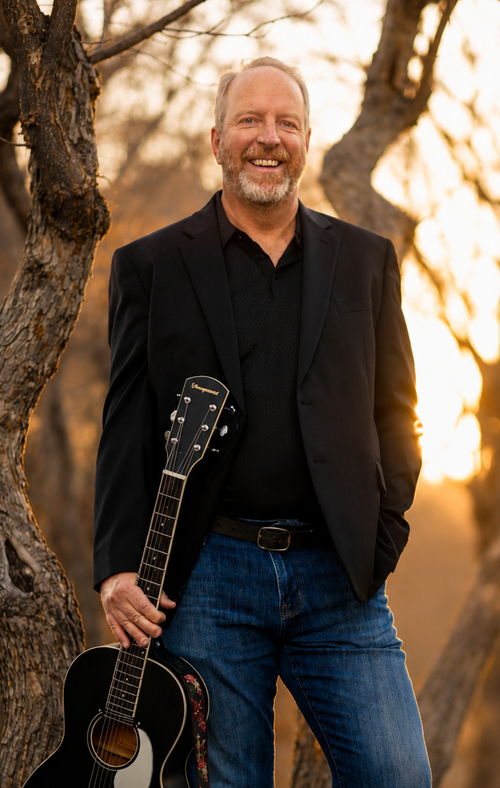 A picture of recording artist Ben Brewer in the woods with a guitar