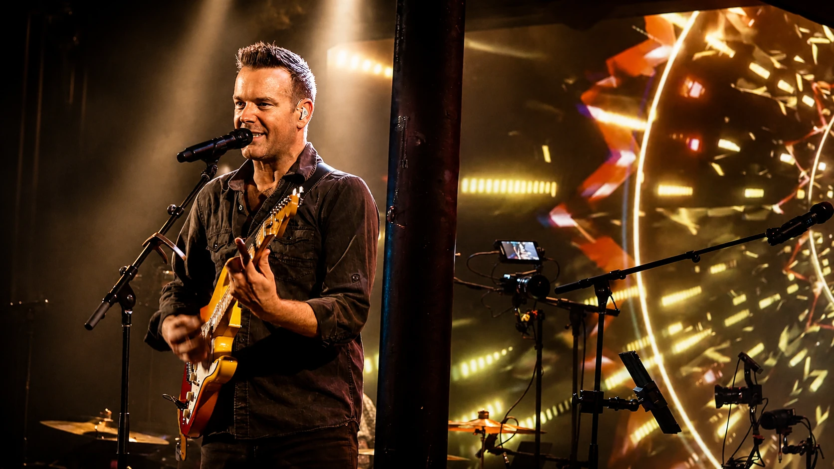 Steve playing electric guitar alongside colorful geometric stage-screen imagery