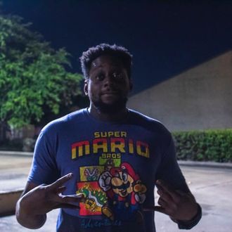 Horten “H20” Ojongtambia, Houston-based dancer, rapper, actor, and choreographer in Legendary Money Team, throwing up west side hand sign in Super Mario shirt selfie.