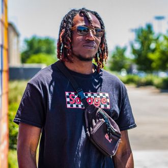 Folajaiye “Beast2Saucy” Akinpelu, Legendary Money Team member and Houston-based streamer, rapper, photographer, actor, and gamer in a Savage shirt, sunglasses, and fanny pack.