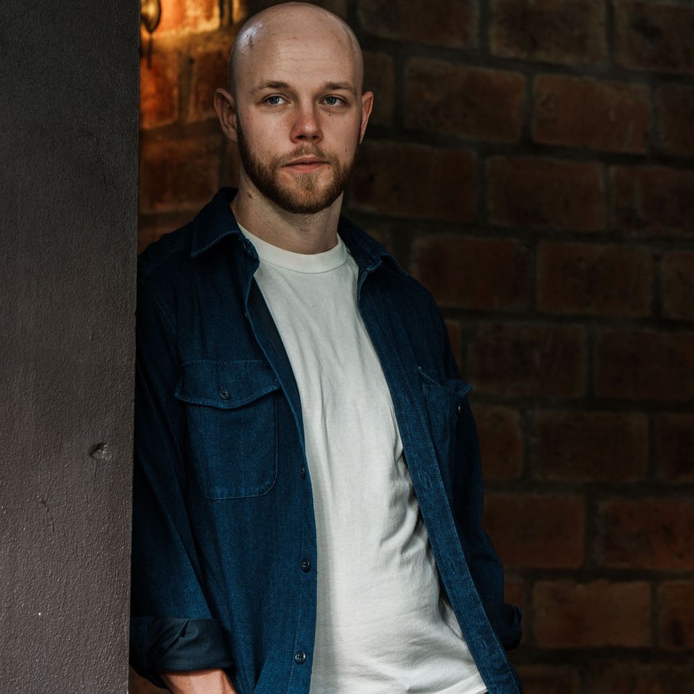 Professional portrait photo of Benkio standing next to a wall.