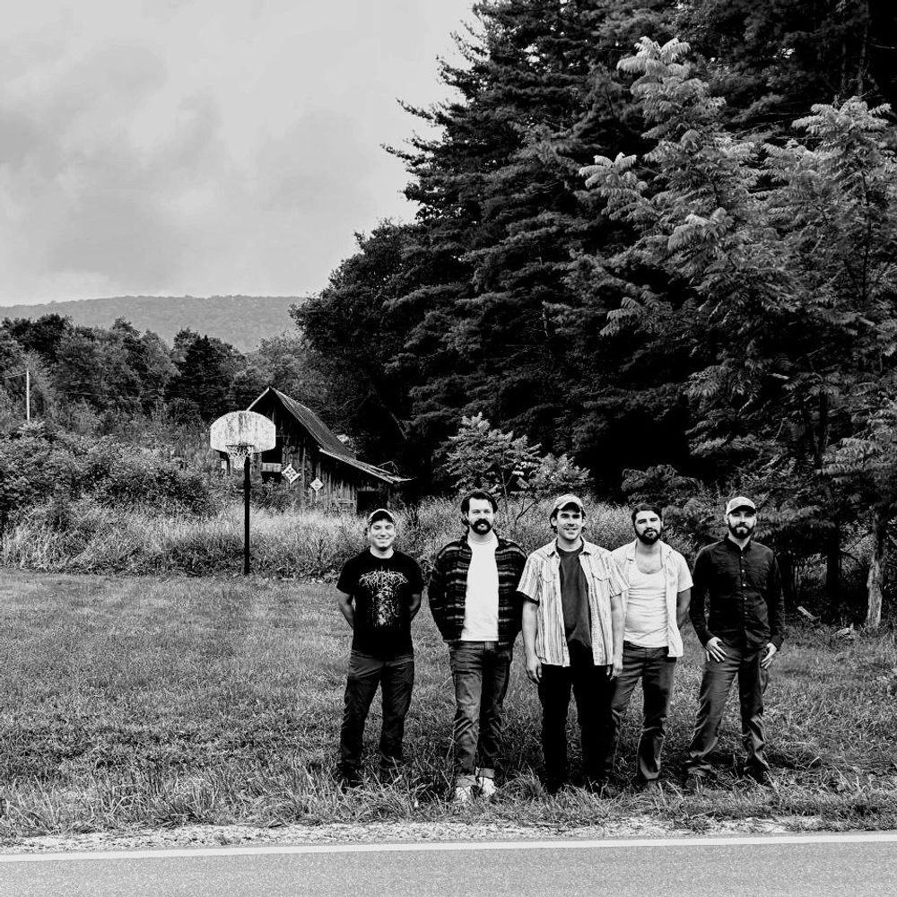 Spell of Leaves members Scott Huffard, Daniel Jones, James Canterbury, Trevor Brown, Matthew Wimberly, stand on the side of Balm Highway in front of an old basketball hoop, abandoned barn.