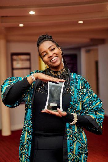 Macharia holding her Community Youth Champion 2025 Award
