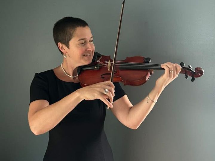 Woman in an classy black dress playing violin at a wedding ceremony
