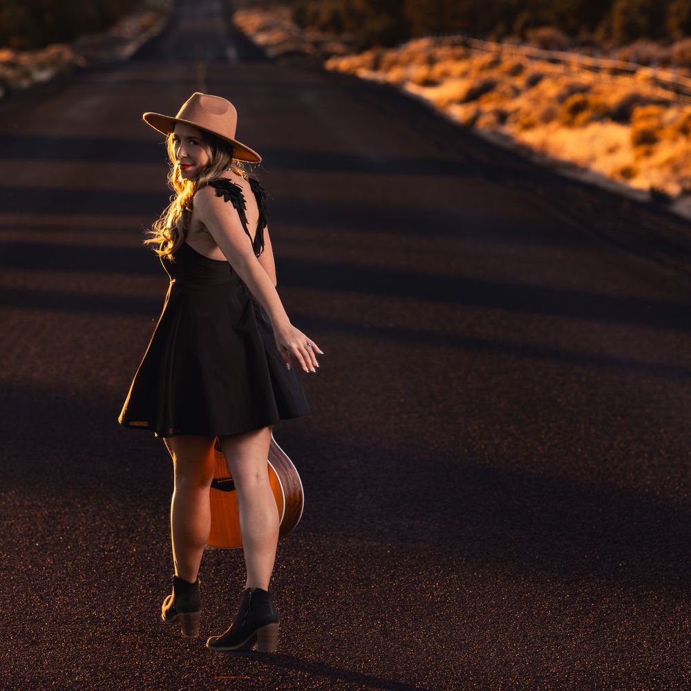 girl in hat with guitar on road