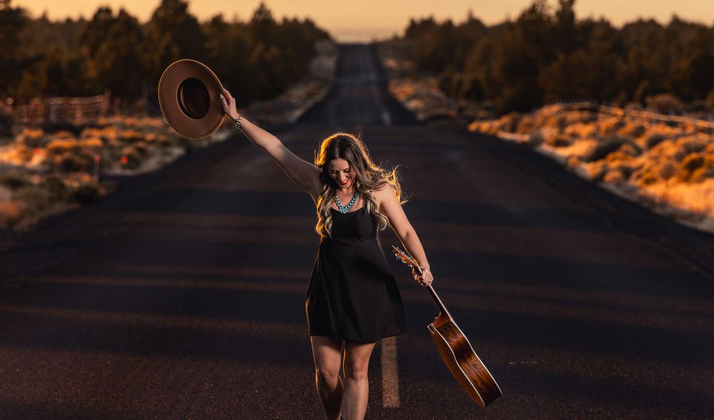 woman with hat in air and a guitar in hand