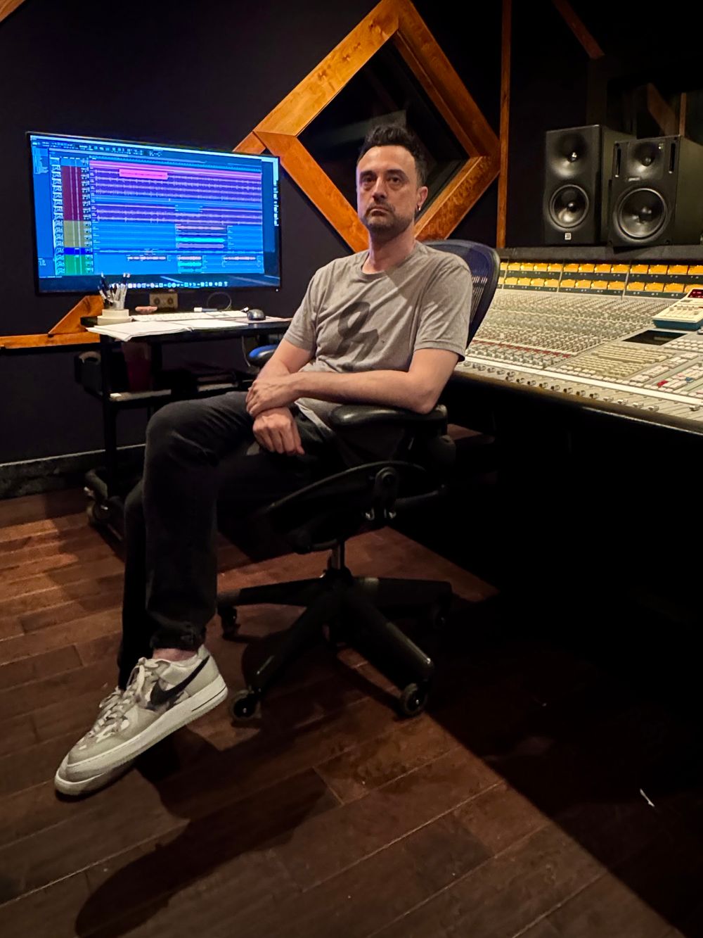 Tyler Rose standing in front of a mixing console in a music studio.