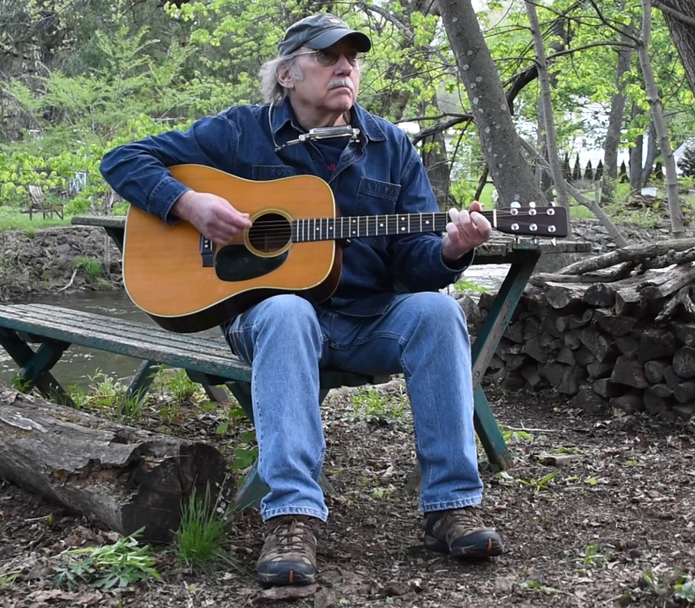 Ken Werner playing guitar while sitting at a picnik table