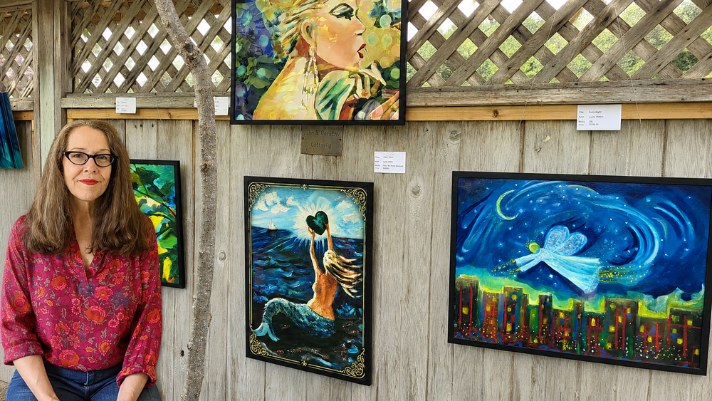 Lucie Walker  with original paintings at an art show.