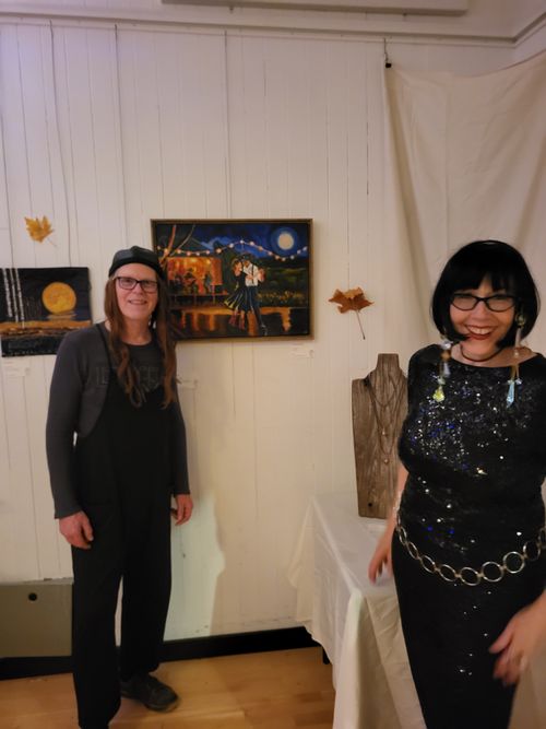 Bass player Bruce Morrison and Lucie Walker standing in front of Lucie's painting, 'The Last Dance of Summer'.