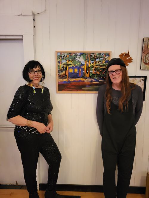 Bass player Bruce Morrison and Lucie Walker standing in front of Lucie's giclee print, 'Magical Mayne'.'