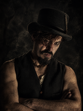 Cheeky Fingers – düsteres Victorian-Noir-Porträt mit schwarzem Zylinder, Bart und verschränkten Armen. Rauch, dramatisches Licht und raue Outlaw-Ästhetik verleihen dem Bild Charakter und Tief