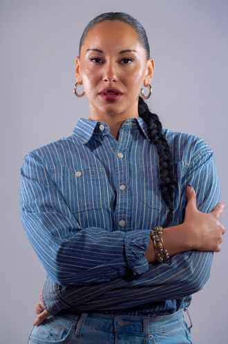 Madison Rose as Sade in blue shirt with arms crisscrossed