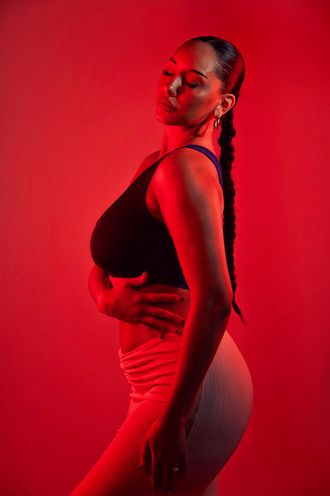 Madison Rose as Sade, eyes closed, posing sideways with arm around waist