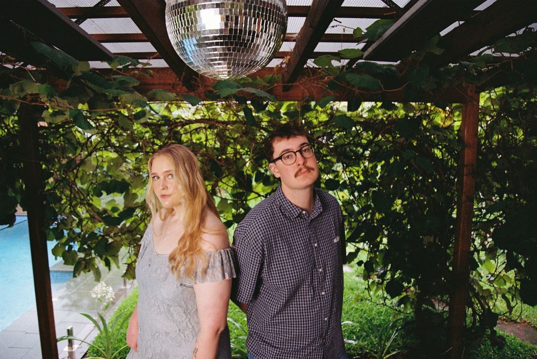 Gabrielle and Clancy McCue under a vine-covered pergola with a disco ball
