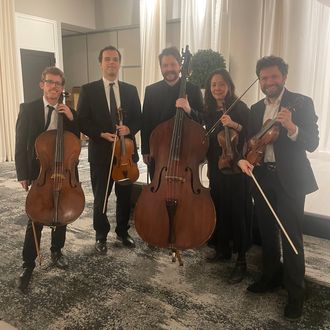 Parkwest Strings string quintet with added lower voice, performing in a grand event space for a cinematic and resonant musical feel.