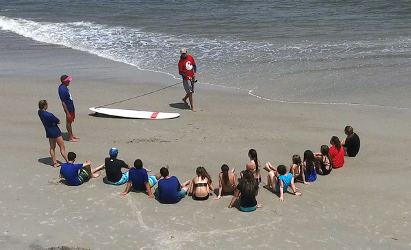 Group surf lesson with smiling students riding waves near Savannah, GA