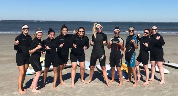 Bachelorette surf lesson with smiling students in wetsuits near Savannah, GA