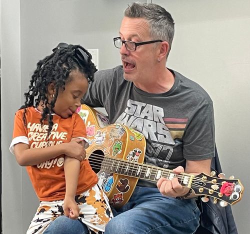 Mr. Patrick with a child holding a dinosaur puppet.