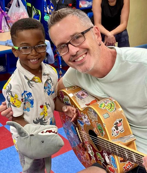 Music With Patrick with a preschool student who is holding a shark puppet