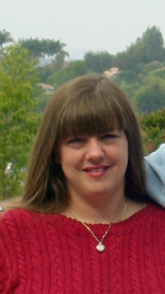 Woman outside smiling on a cloudy day.