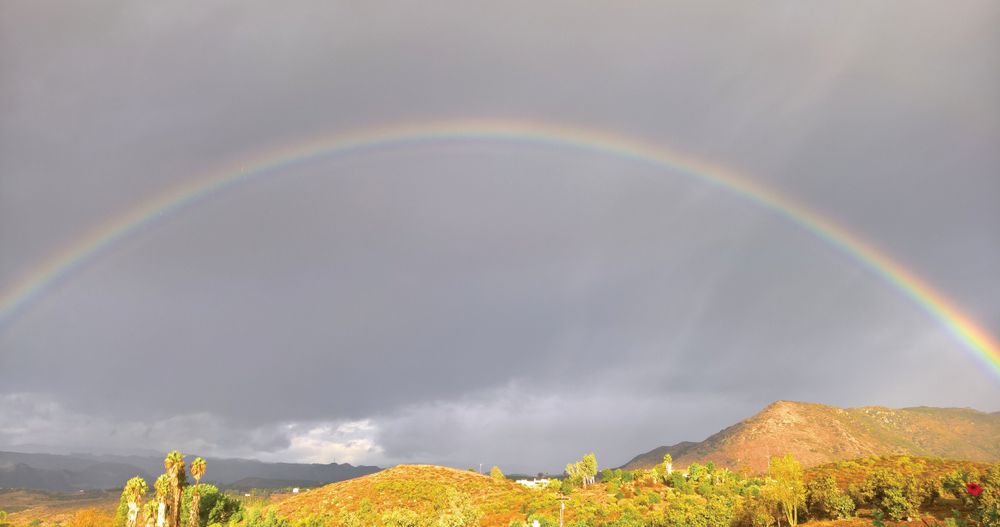 A rainbow in the gray cloudy sky