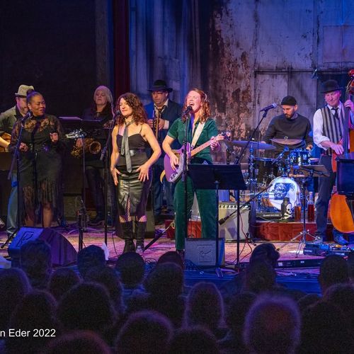 Bre Gregg performing live on stage for collaborative musical tributes and community events.