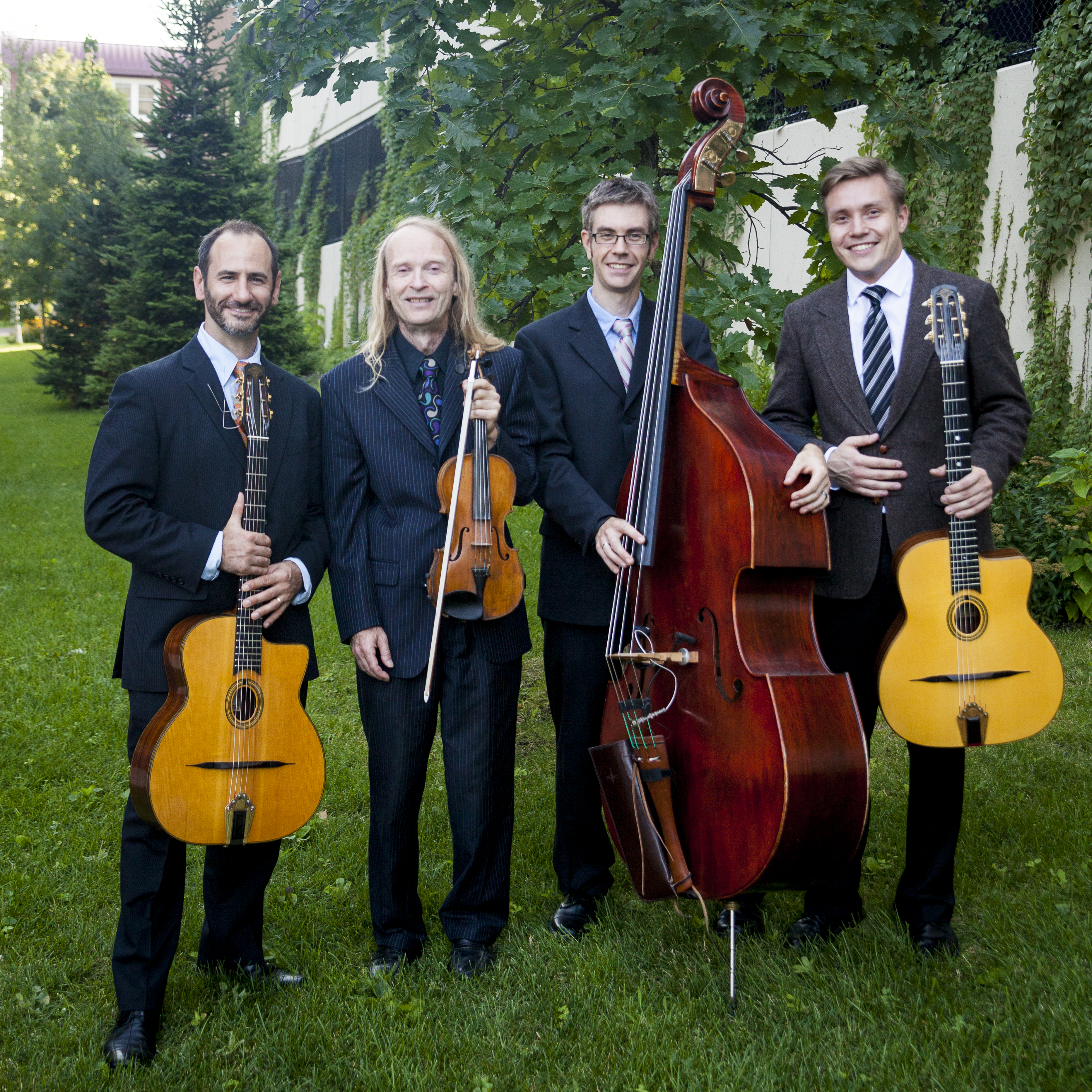 Photograph of the Twin Cities Hot Club standing in a garden.  Robert Bell, guitar + bandleader.  Gary Schulte, violin.  Matt Peterson, bass.  Stan Ponkin, guitar.