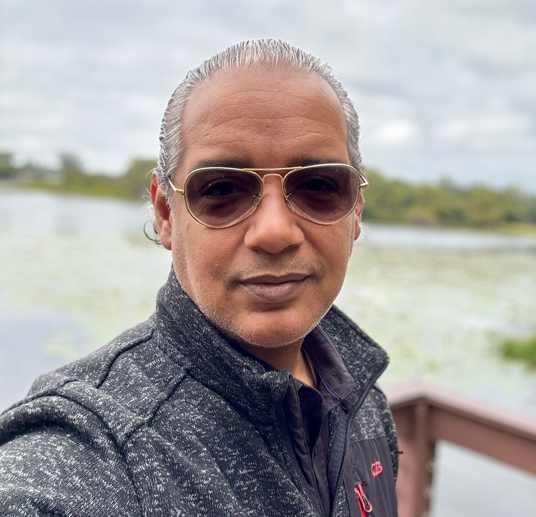 Alcides Duverge frente al lago Sybelia, sonriendo a la cámara con el paisaje detrás